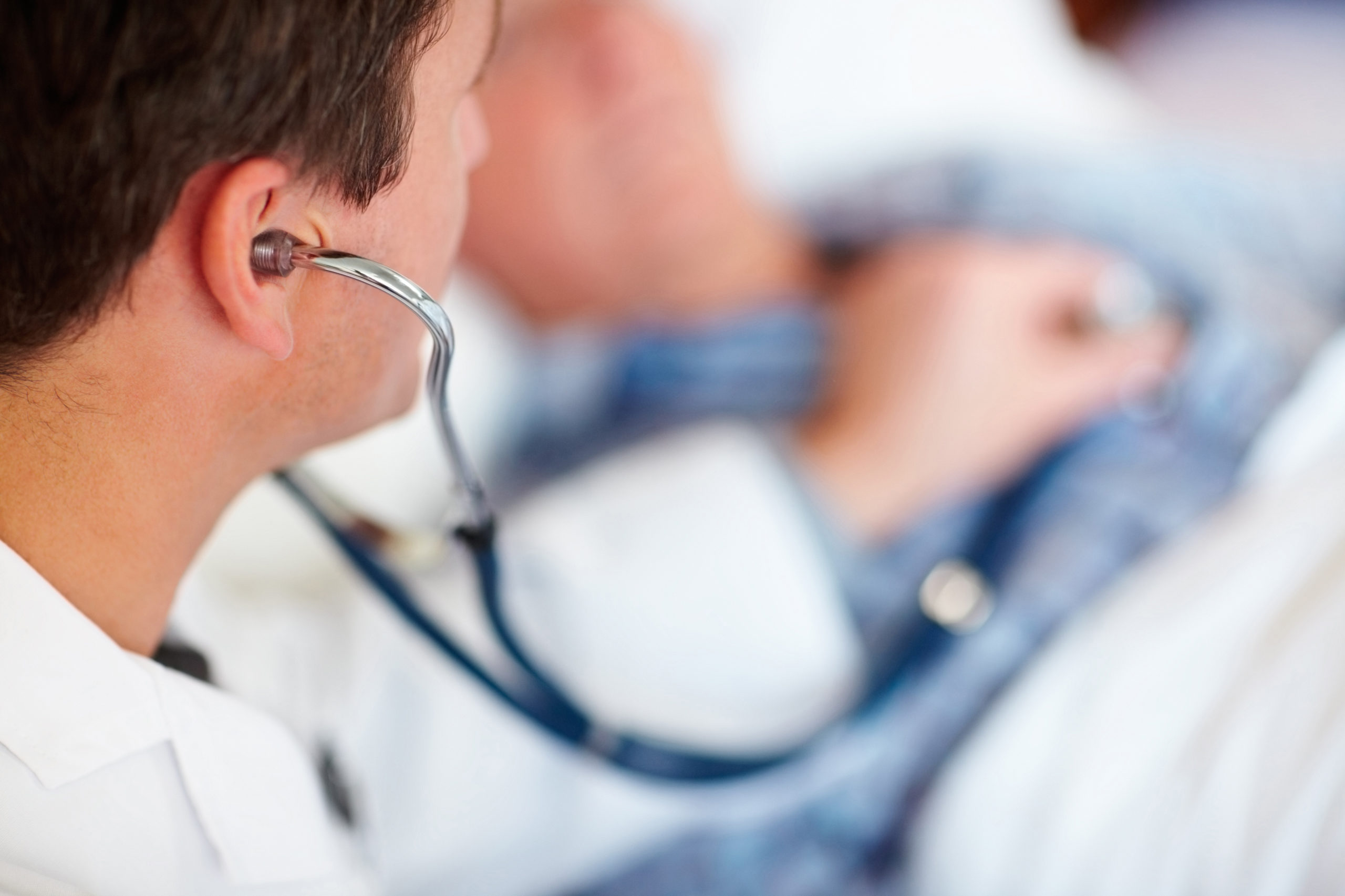 Male doctor listening to a patient's heart beat with a stethoscope