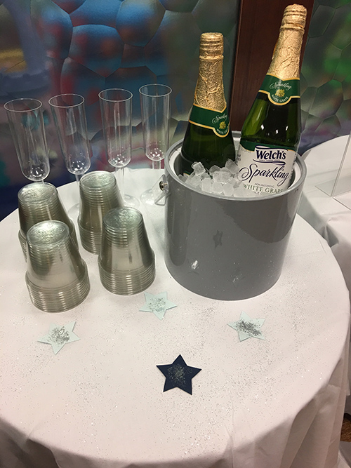 A table with drinkware and bottles of sparkling grape juice