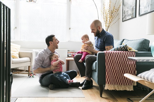 Two fathers with their two babies in living room