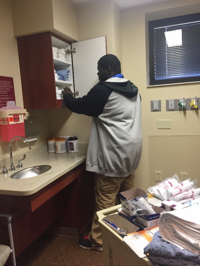 Male hospital intern adding supplies to cabinet in hospital room