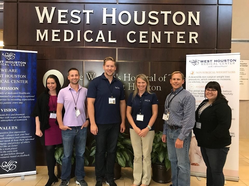 A group of Human Resources staff members standing by West Houston Medical Center sign