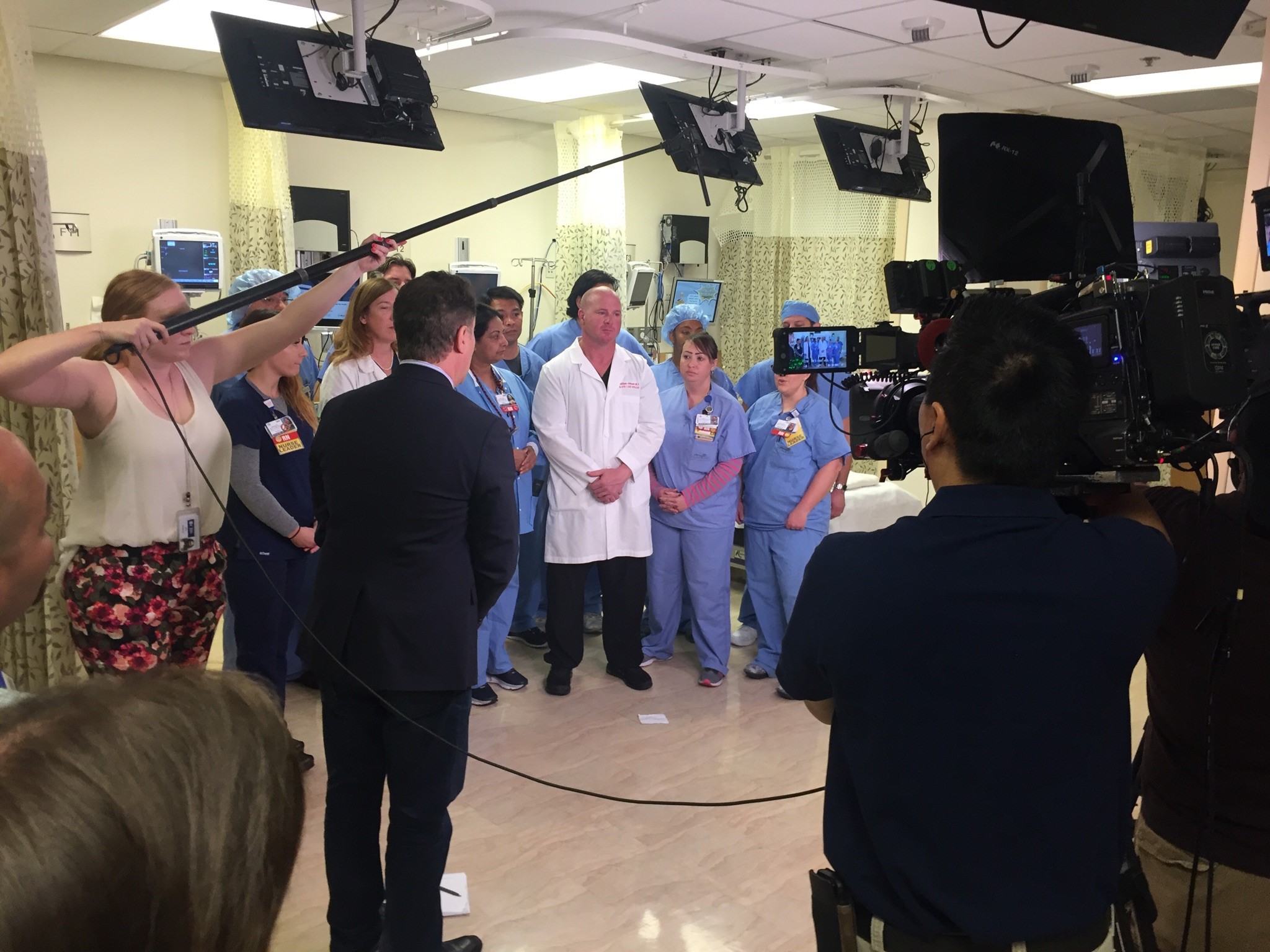 A group of hospital caregivers standing in front of TV cameras