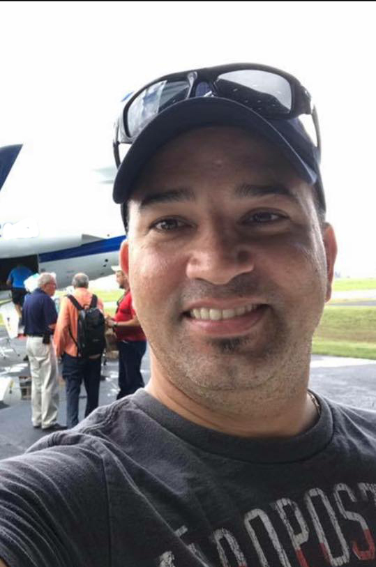 Man wearing baseball cap standing in front of airplane
