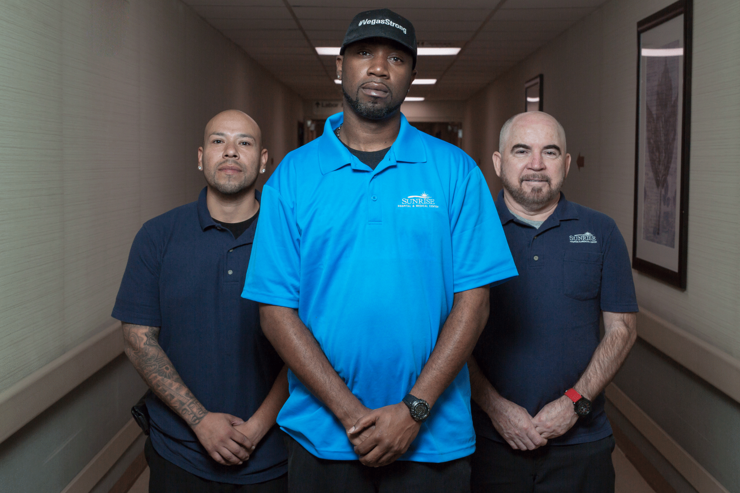 Three men wearing polos standing in hospital hallway