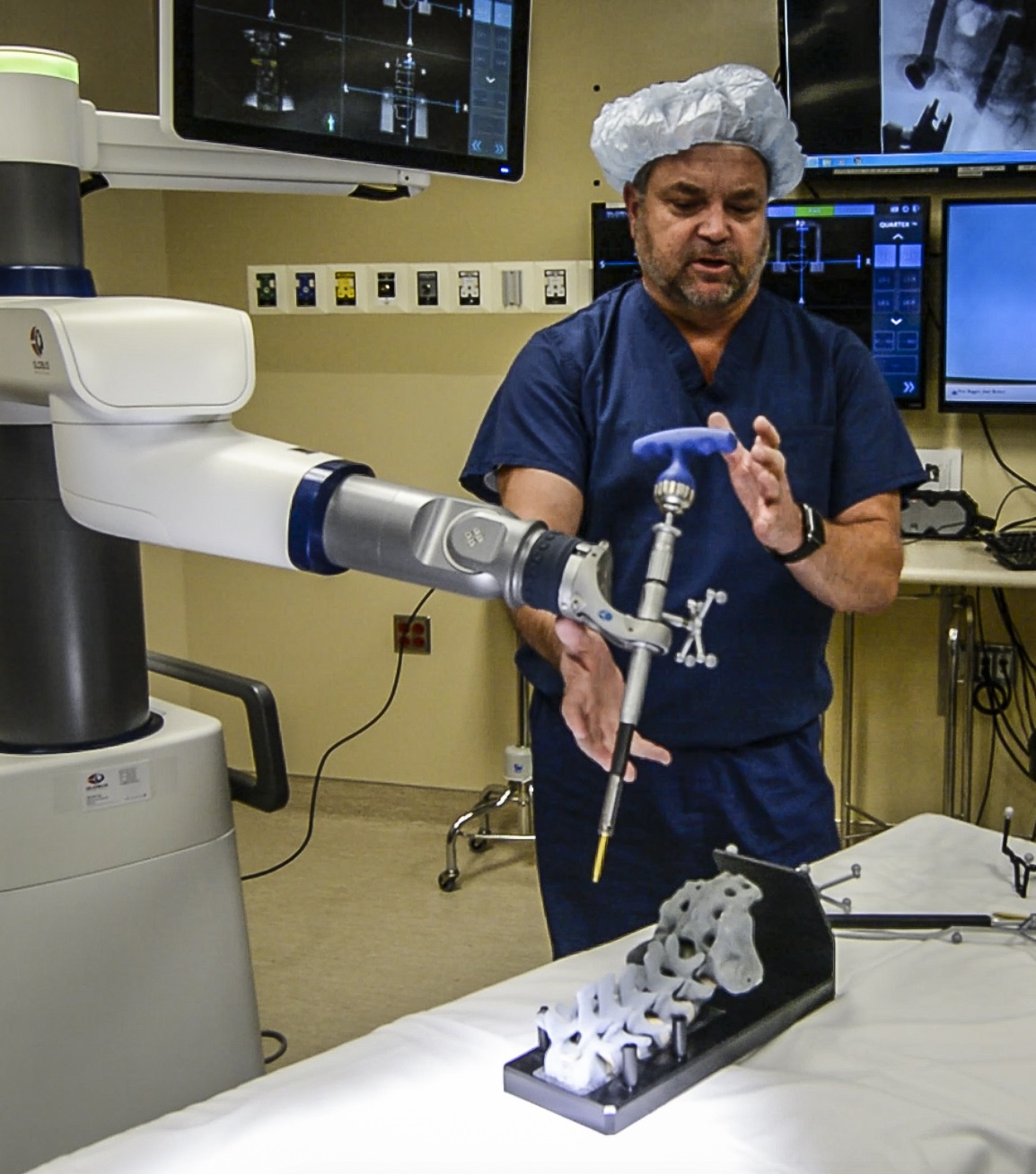 Male doctor wearing scrubs working with surgical robot