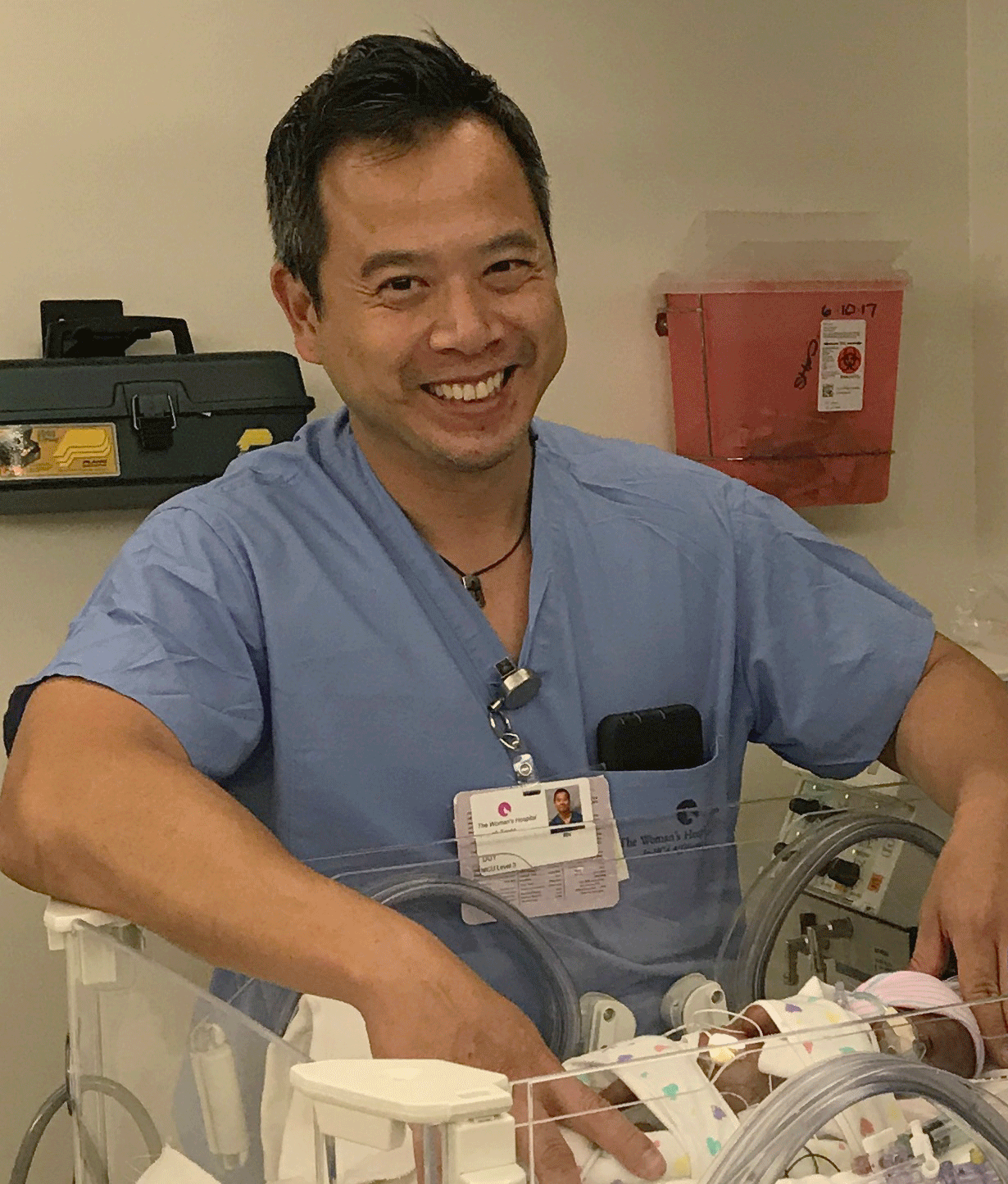 Male nurse checking on baby in hospital incubator