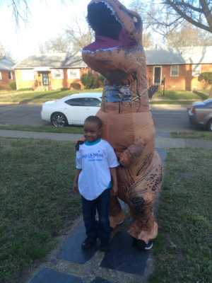 Boy posing with someone in a dinosaur costume