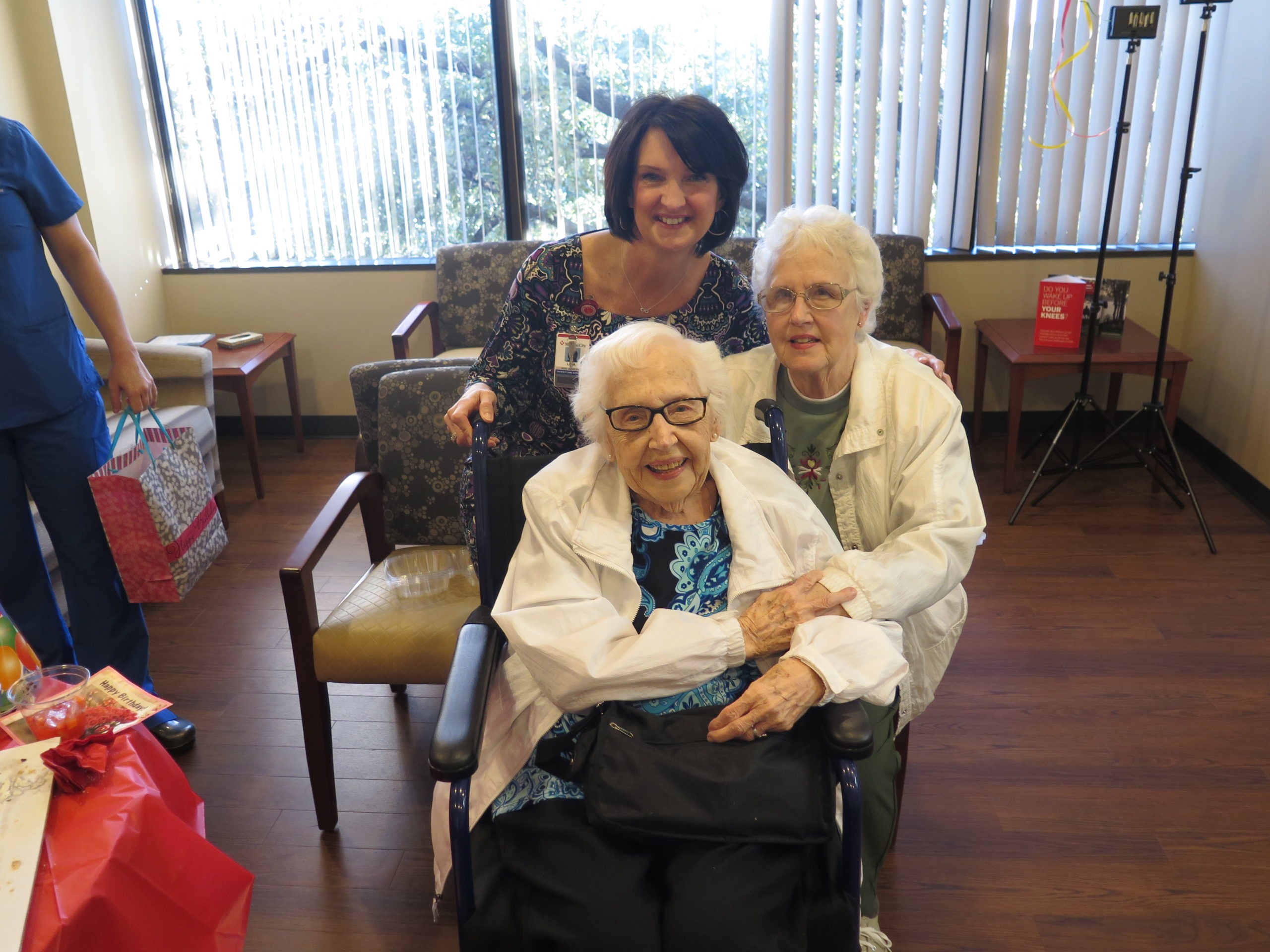 99-year-old patient posing for photo with family member and nurse