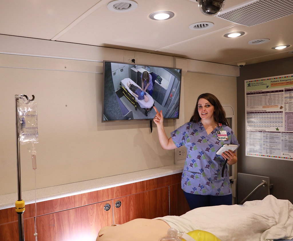 Female nurse pointing at TV monitor showing training video