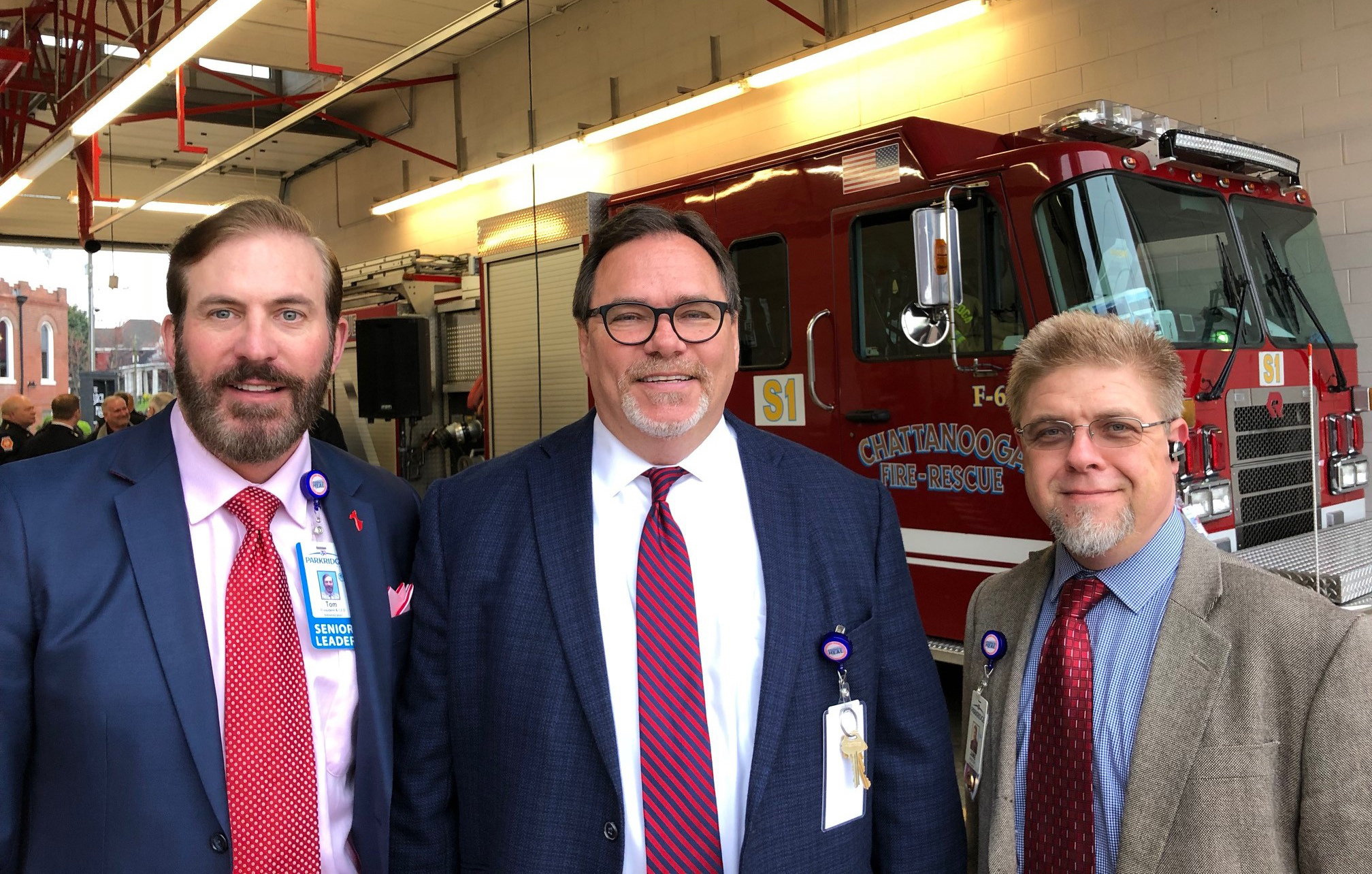 Three men in suits and ties standing in front of a firetruck