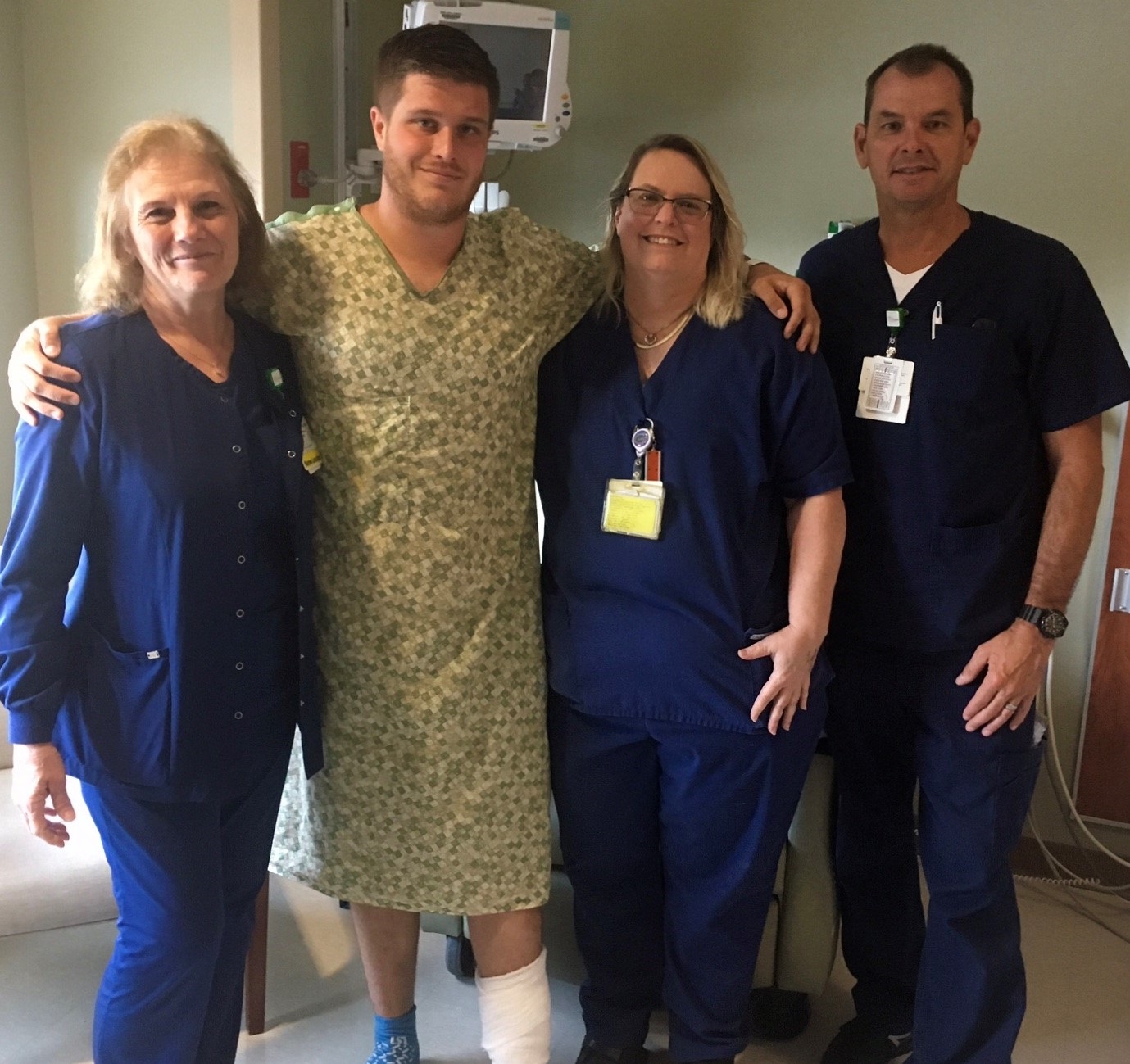 Three nurses standing with a male patient in hospital gown