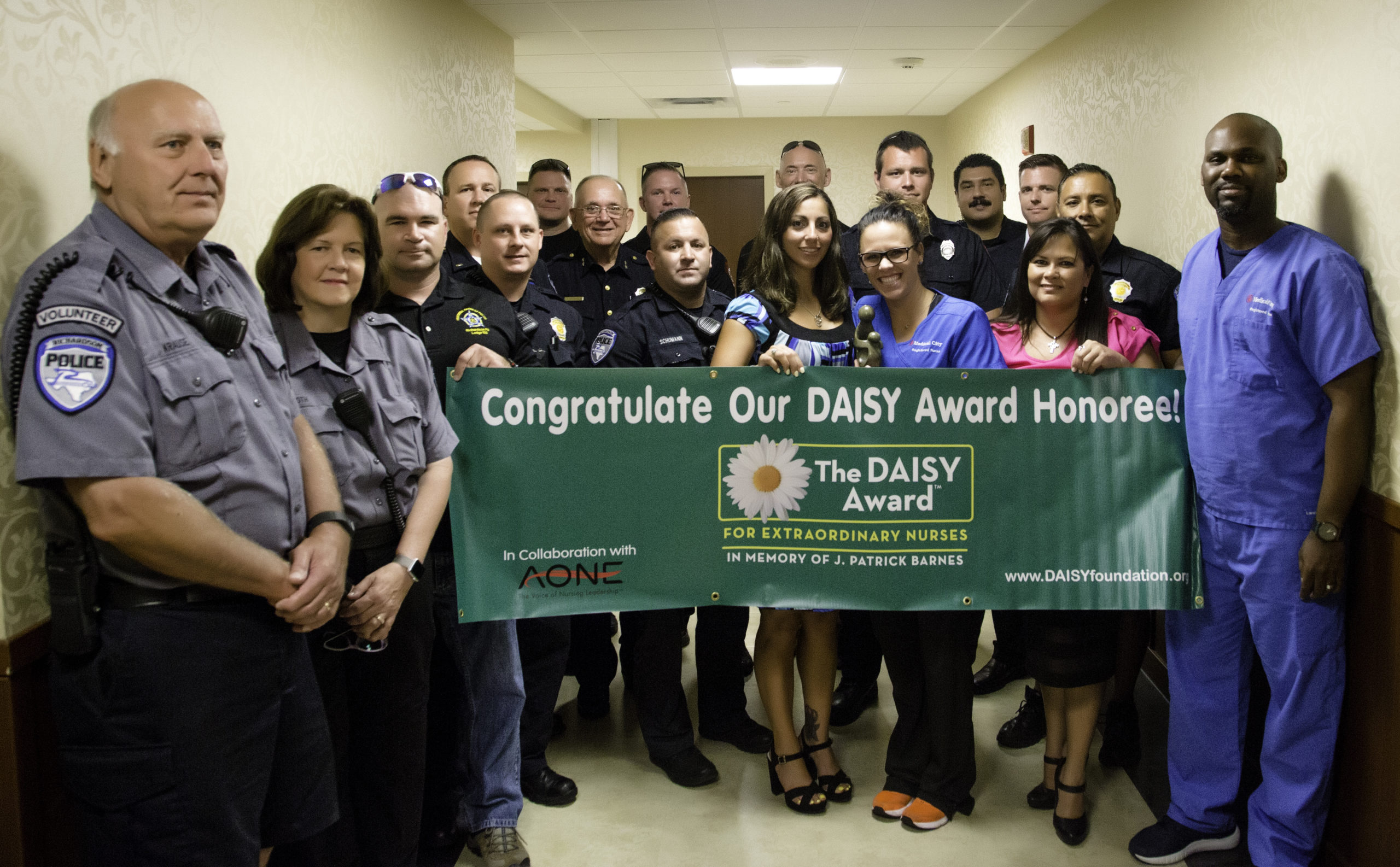 Group of police officers and hospital workers with a Daisy Award banner