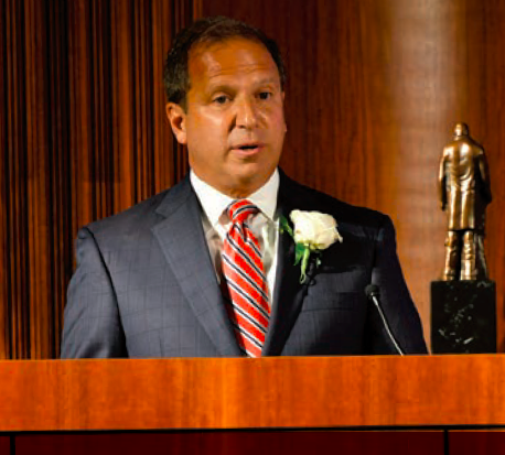 Man in suit and tie speaking at podium