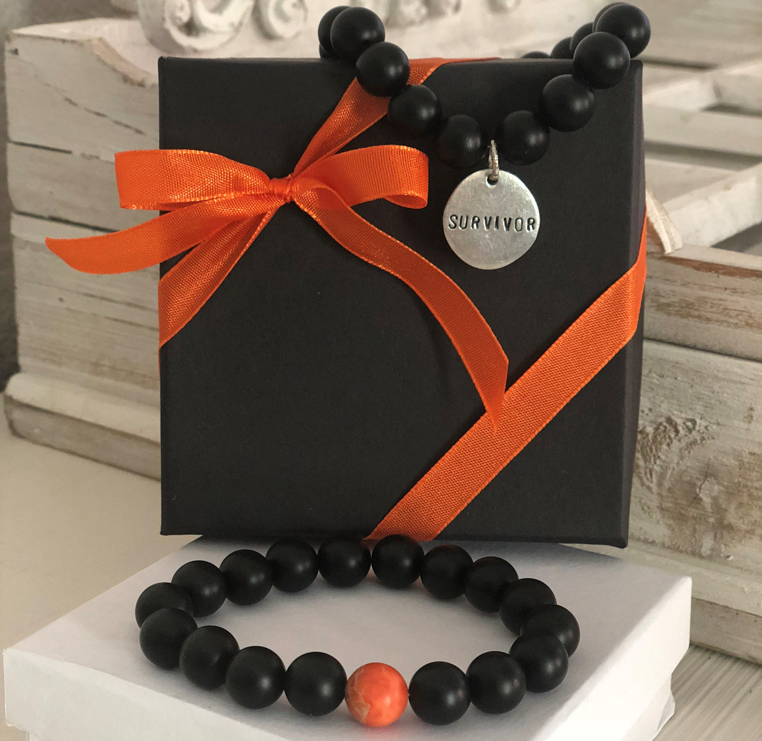 Bracelets made of black and orange beads and a pendant that says Survivor