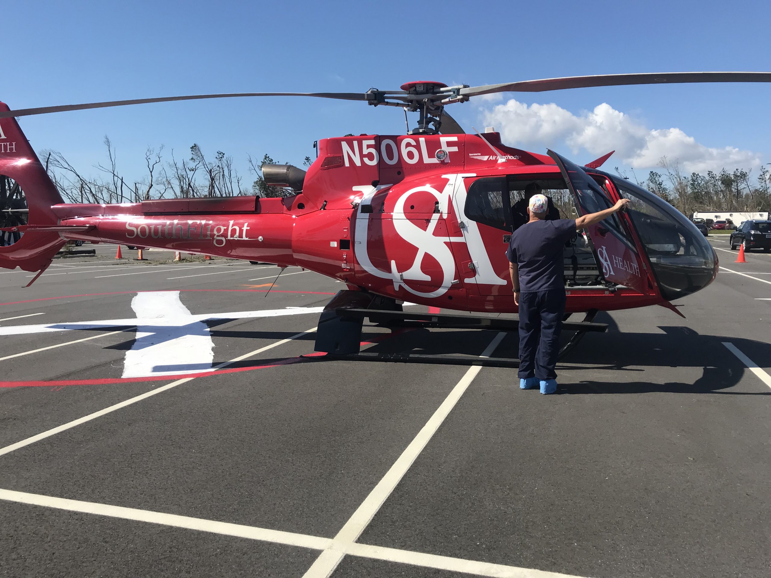 Man standing outside red medical helicopter