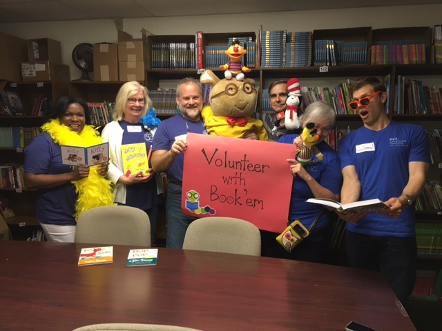A group of volunteers holding books and plush character toys