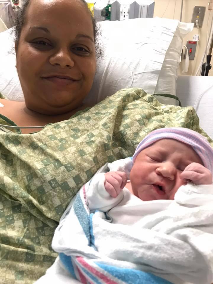 Mom holding newborn baby in hospital bed