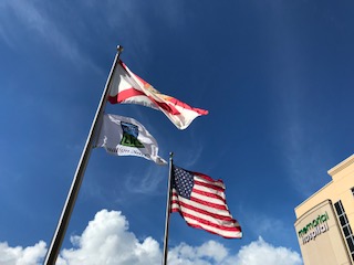 American flag, Florida state flag and Donate Life flag flying outside hospital