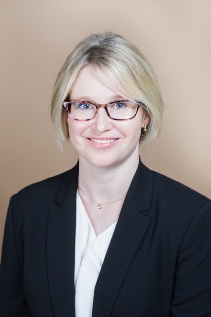 Woman wearing glasses and suit jacket. Headshot of Alexa Clapp.