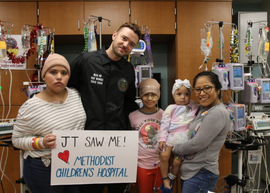 Justin Timberlake posing with three young cancer patients and a parent