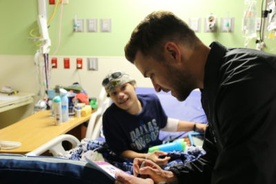 Justin Timberlake signing a piece of paper for a young cancer patient