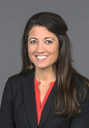 Woman wearing black suit jacket and red top.