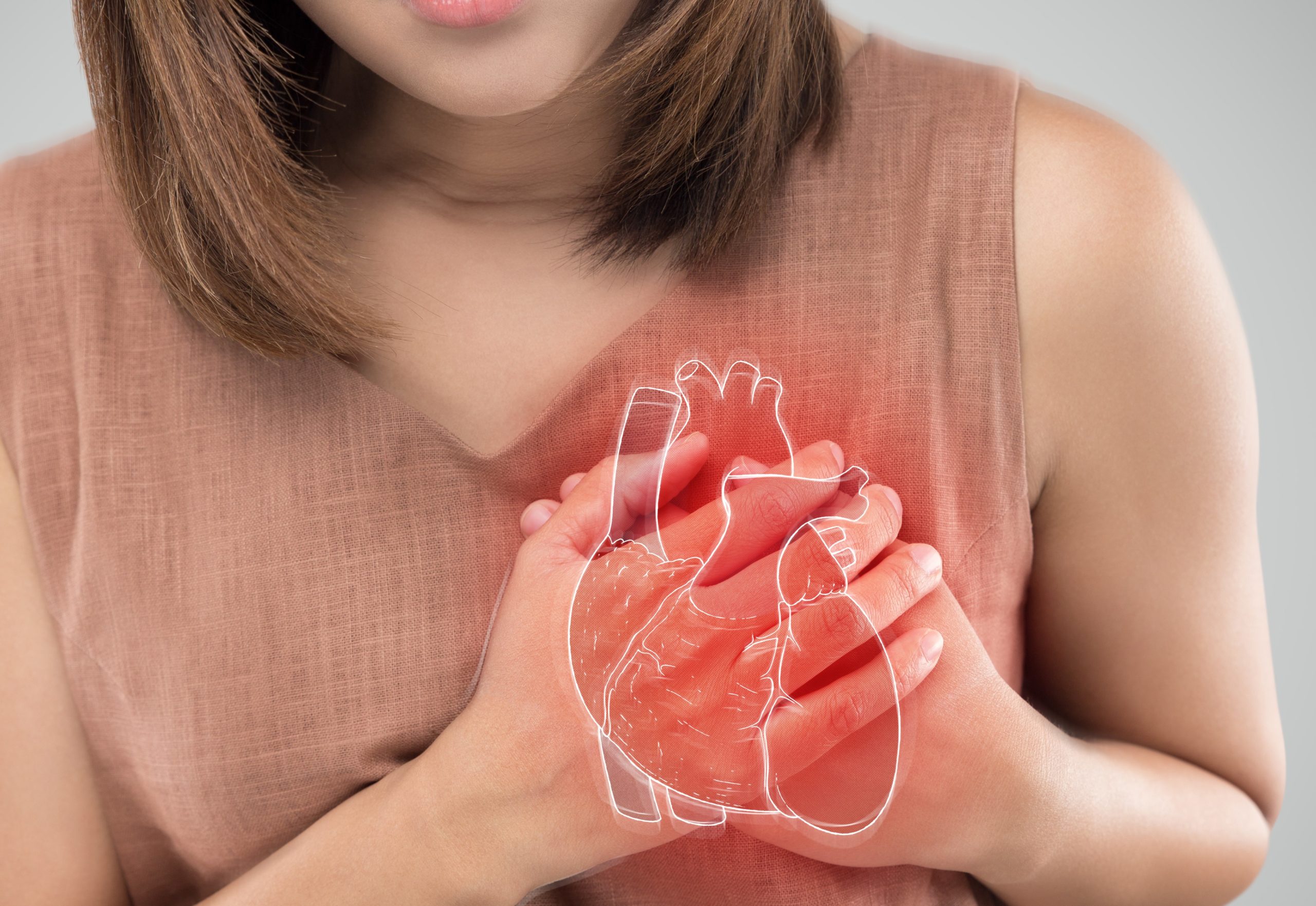 Woman holding the left side of her chest with an anatomical heart drawn over her hands