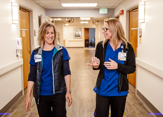 Two female nurses walking down hospital hallway