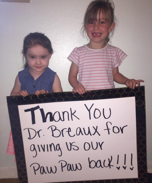 Two girls holding sign that says Thank you Dr. Breaux for giving us our paw paw back