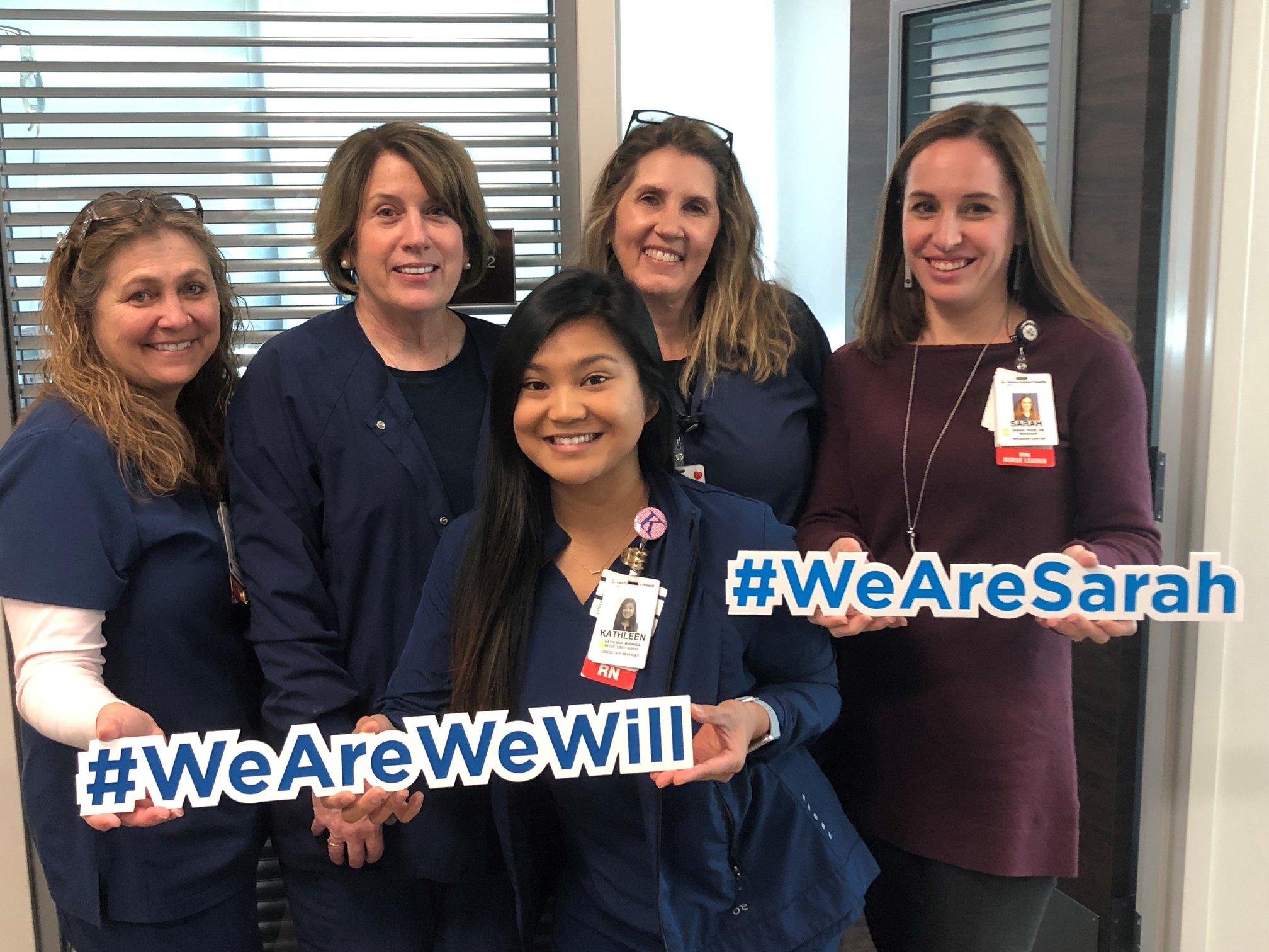A group of nurses holding signs that say #WeAreWeWill and #WeAreSarah