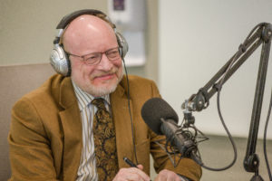 A man wearing headphones and sitting in front of a microphone
