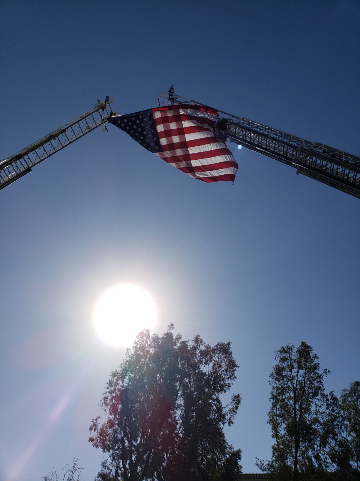An American flag raised between two firetruck ladders