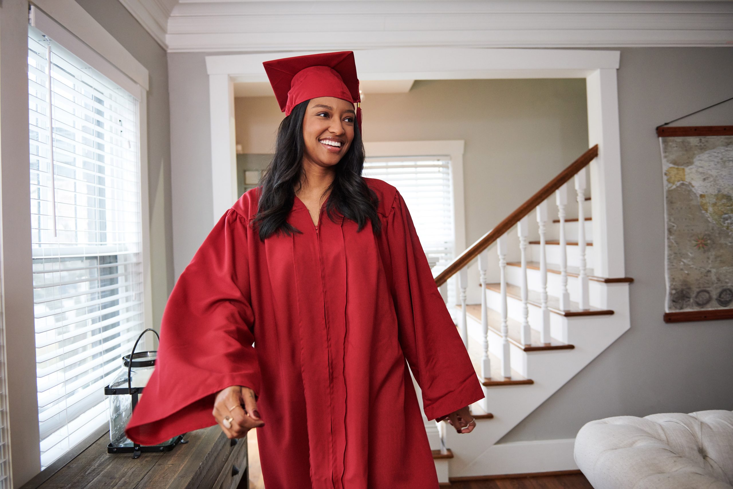 Young woman wearing red graduation cap and gown