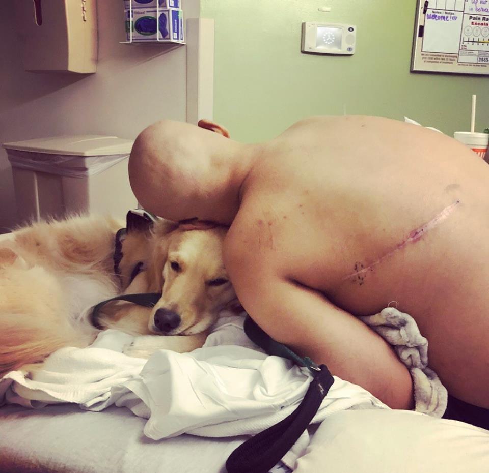 A hospital patient leaning down and resting their head on a therapy dog