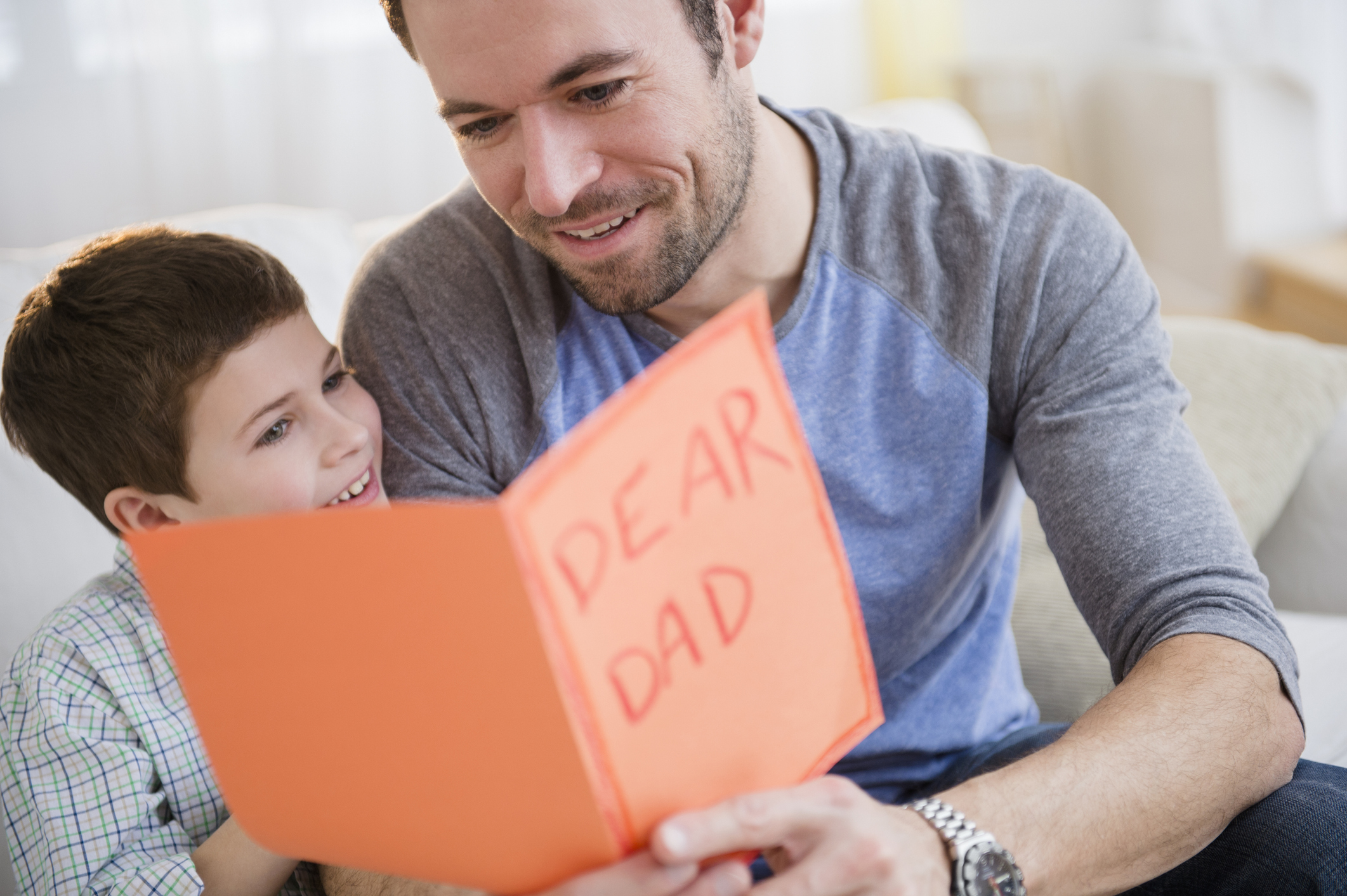 A man sitting next to his son while reading a Father's Day card