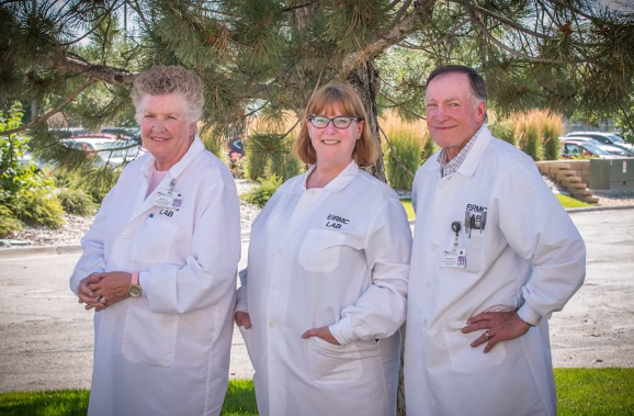Three medical professionals standing together while wearing white lab coats