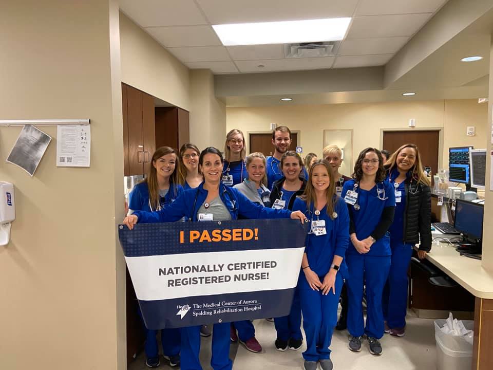 A group of nurses at The Medical Center of Aurora holding a sign celebrating a new nationally certified registered nurse