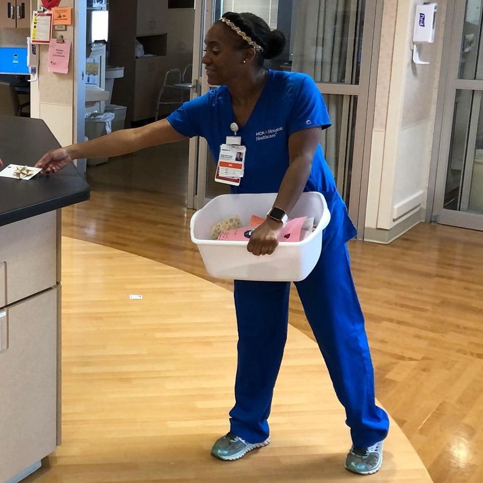 Ashanti Norris wearing scrubs, holding a plastic bin and placing a gift card on a counter
