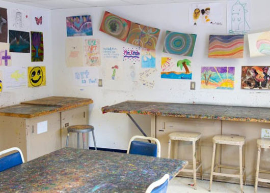Art room with counters, stools and children's art on the walls 