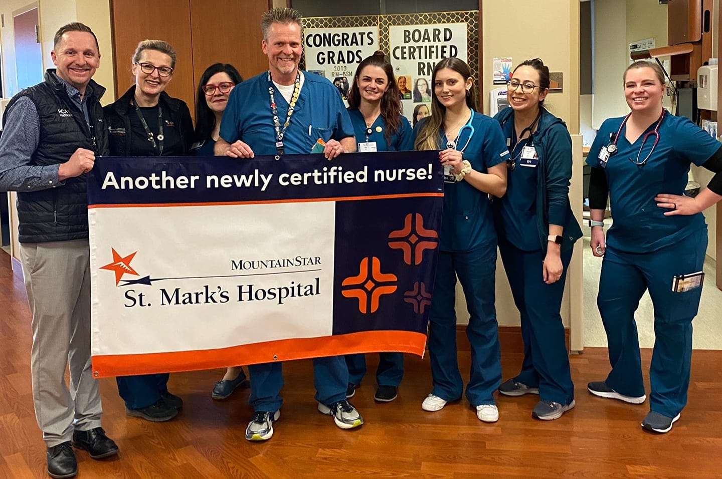 A group of nurses at St. Mark's Hospital hold a sign celebrating a newly certified nurse