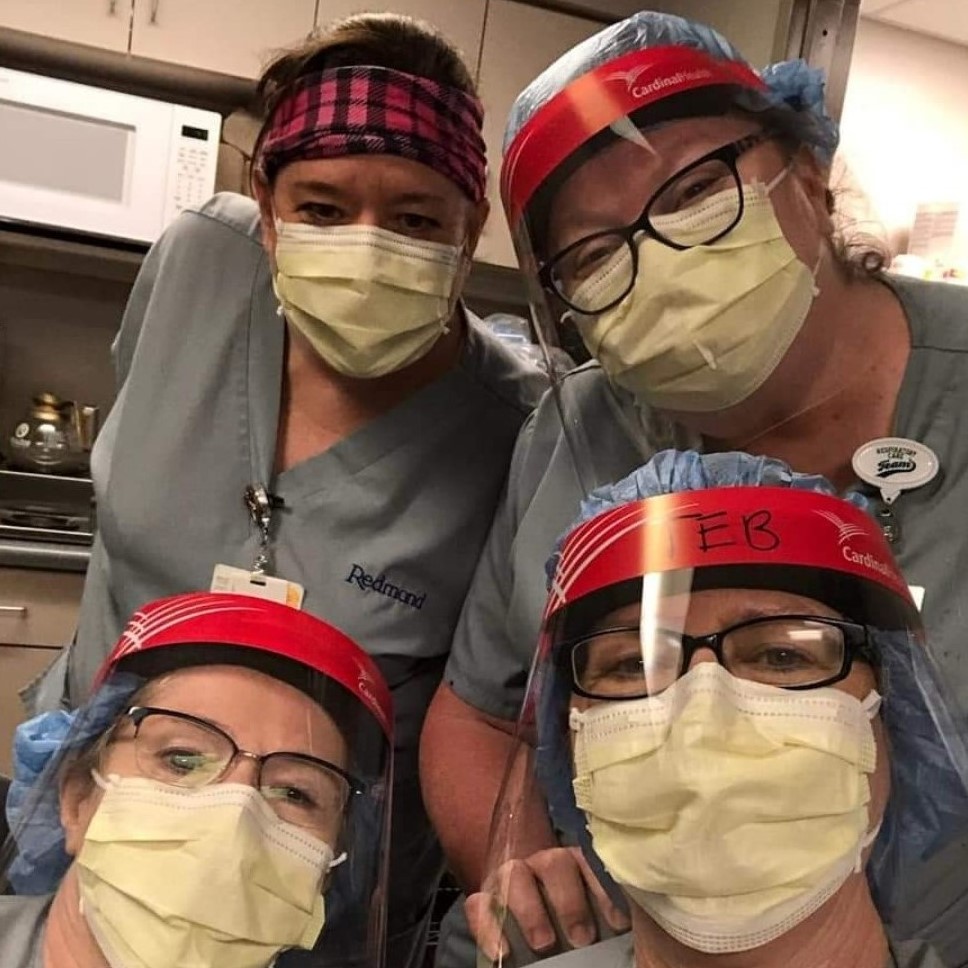 Four medical professionals wearing scrubs, protective face masks and face shields