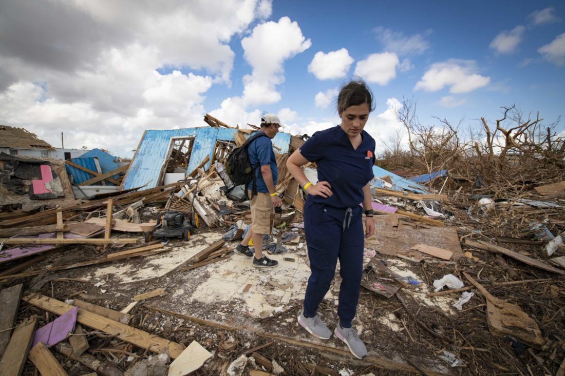 A man and a woman walk around rubble from homes destroyed by a storm
