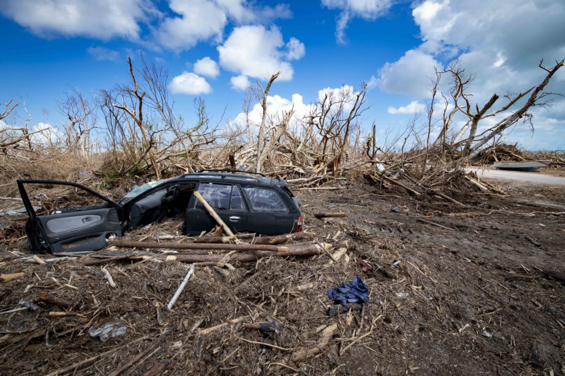 An automobile sits submerged in  wood and rubble after a storm 
