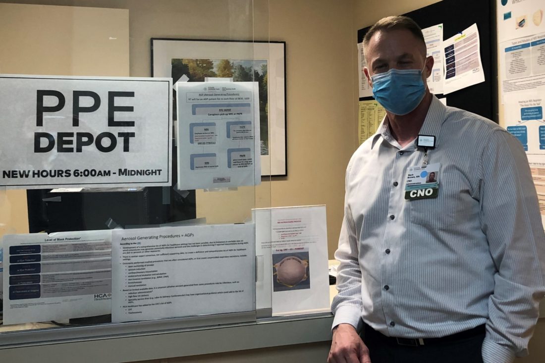 Man wearing face mask standing next to a sign that says PPE Depot