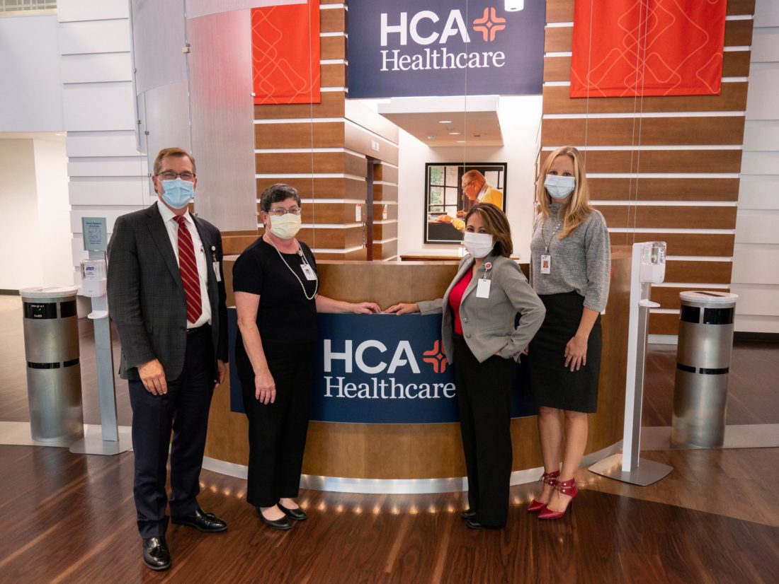 Four people standing next to HCA Healthcare sign