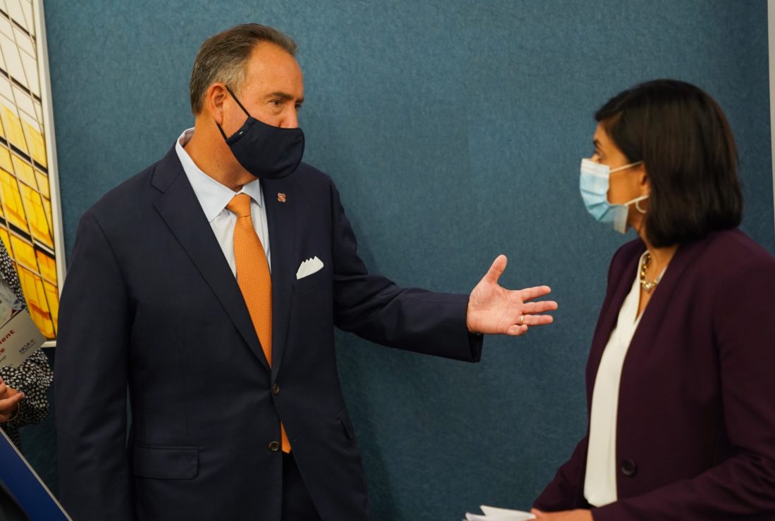 A man and woman talking while both wearing face masks. 