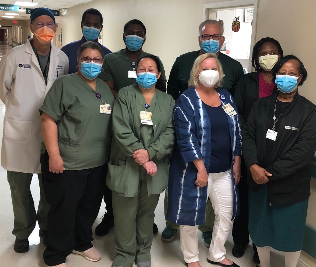 Group of pharmacy colleagues wearing face masks standing in a hospital hallway