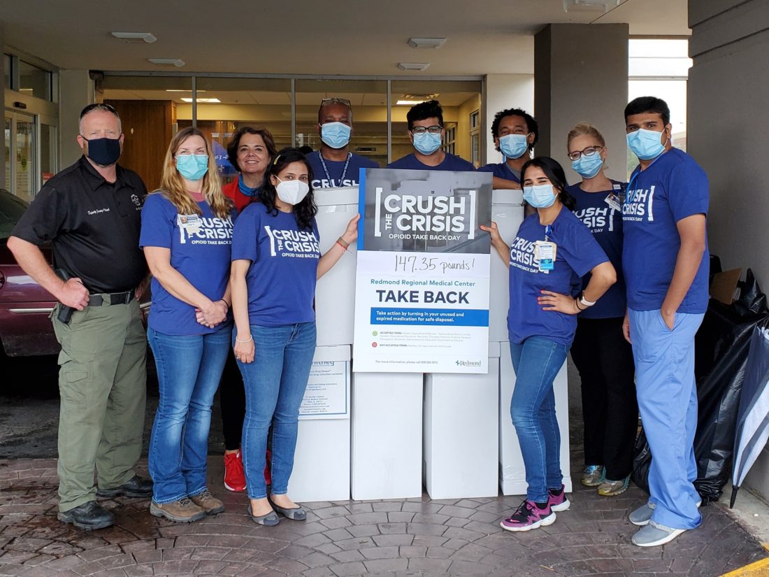 Ten people wearing face masks standing with a Crush the Crisis sign