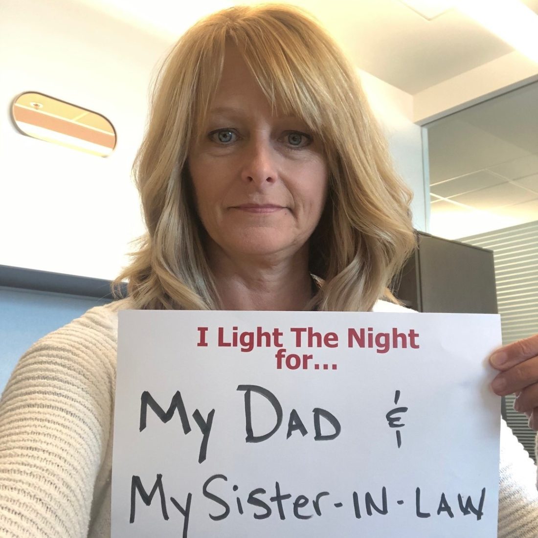 Woman holding sign that says I Light the Night for My Dad and My Sister-in-Law. 