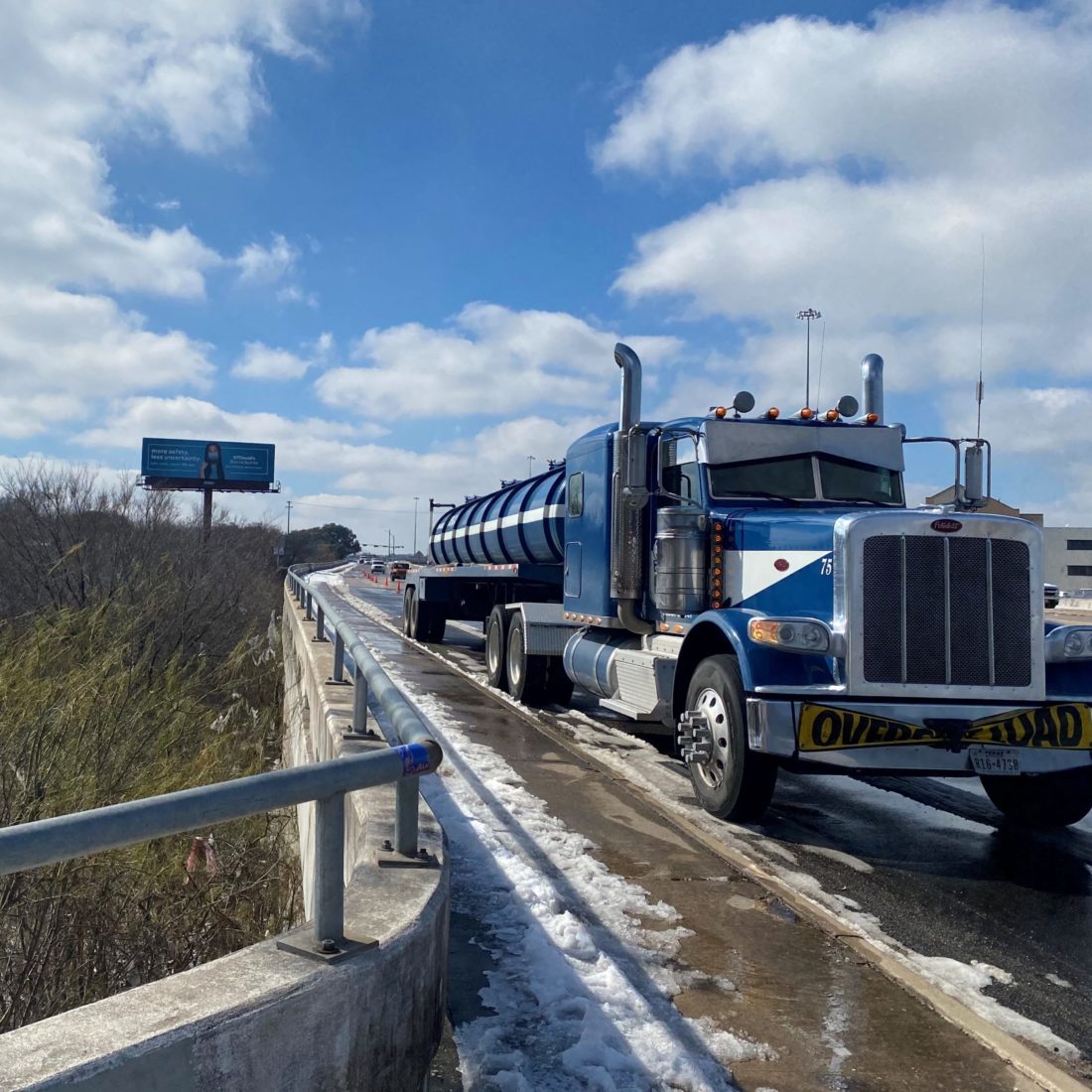 Blue water tanker truck on a snowy road on a sunny day